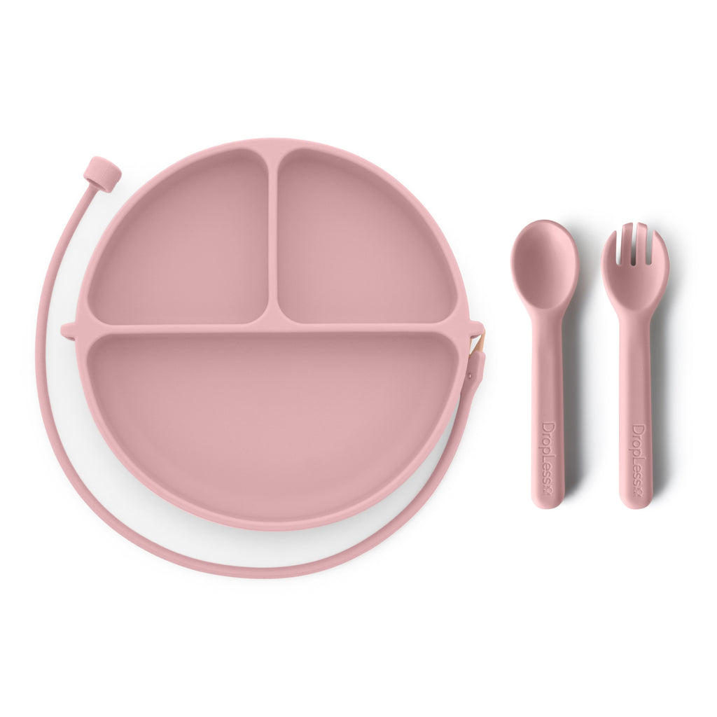 Pink silicone plate with divided sections and matching spoon and fork on a white background