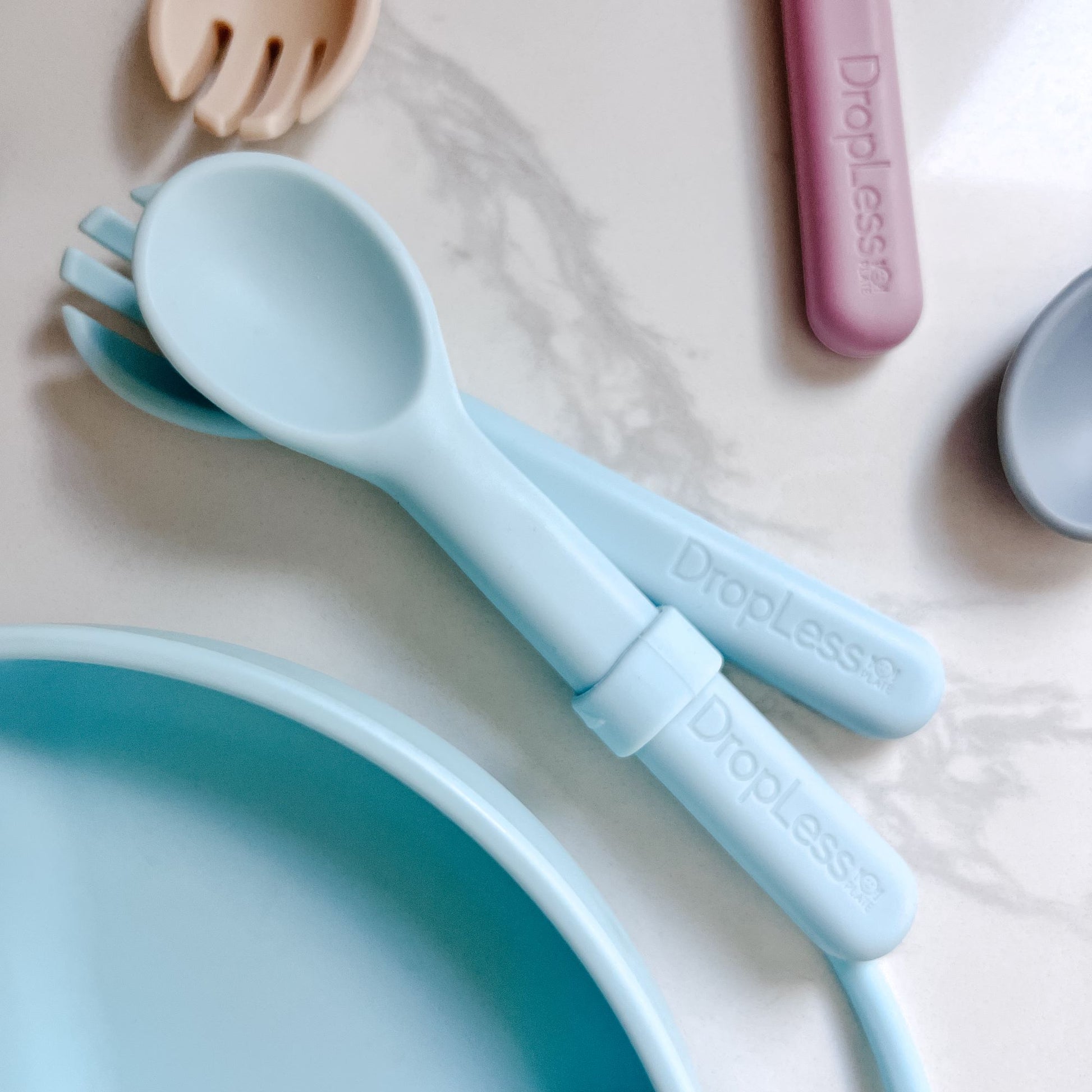 Light blue spoon and fork set with 'Dropless' branding on a light background
